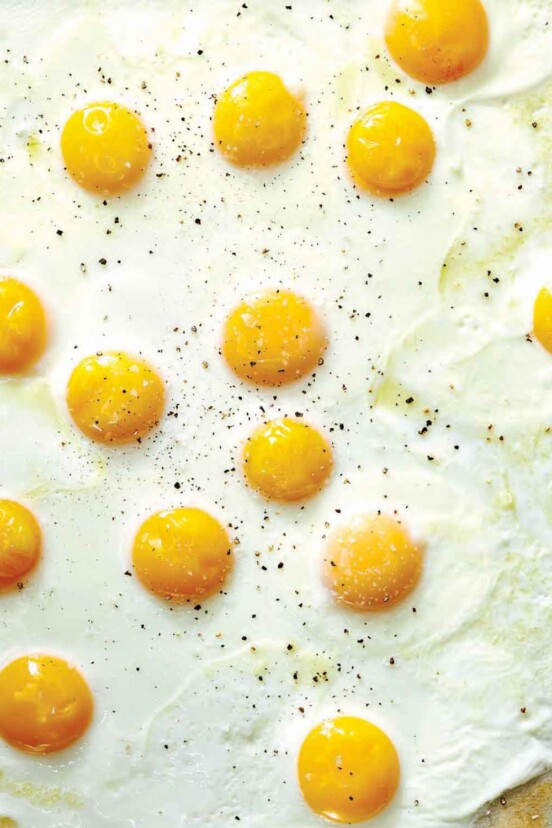 Sunny side up sheet pan eggs on a baking sheet.