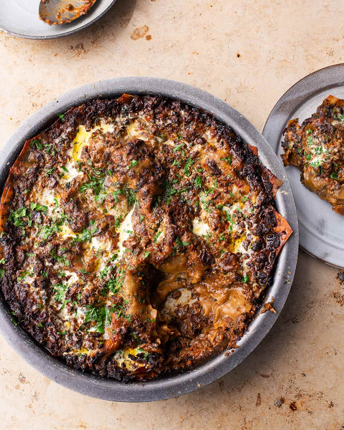 A round dish filled with spicy mushroom lasagna and a serving on a plate beside it.