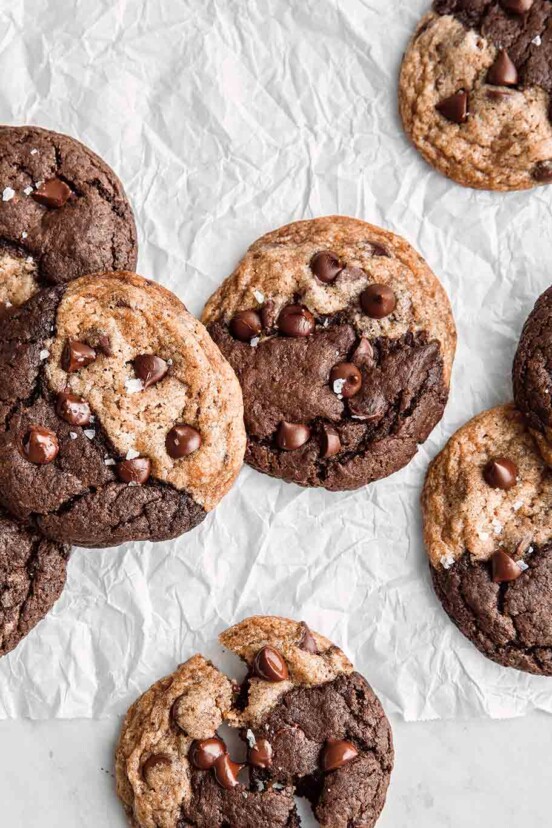 Eight vegan chocolate chip brownie swirl cookies on a piece of crumpled parchment.