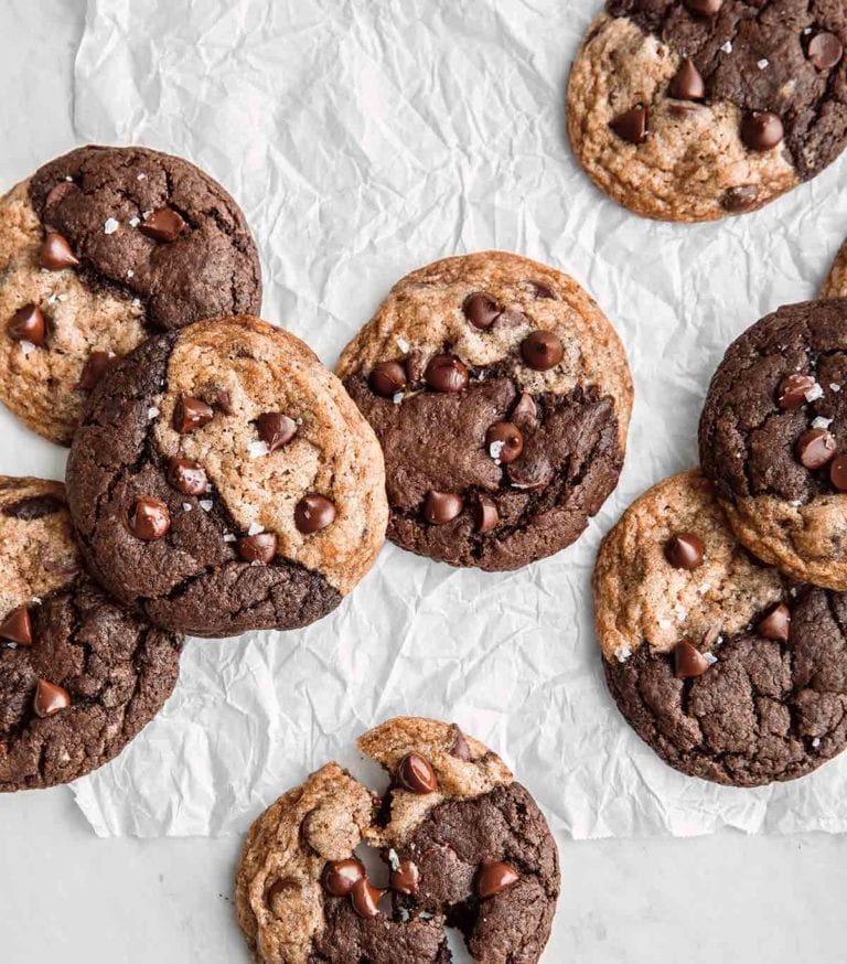Eight vegan chocolate chip brownie swirl cookies on a piece of crumpled parchment.