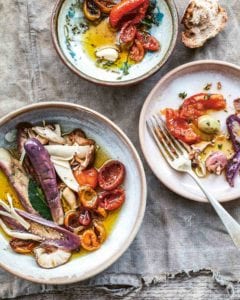 Mushrooms, eggplant, and tomatoes in a bowl and two vegetable antipasti plates.