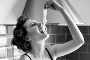 A woman eating spaghettin noodles in her underwear to illustrate 10 life lessons learned in the kitchen.