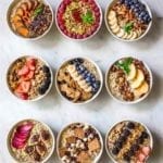 Nine bowls of oatmeal, each topped with different combinations of best oatmeal toppings.