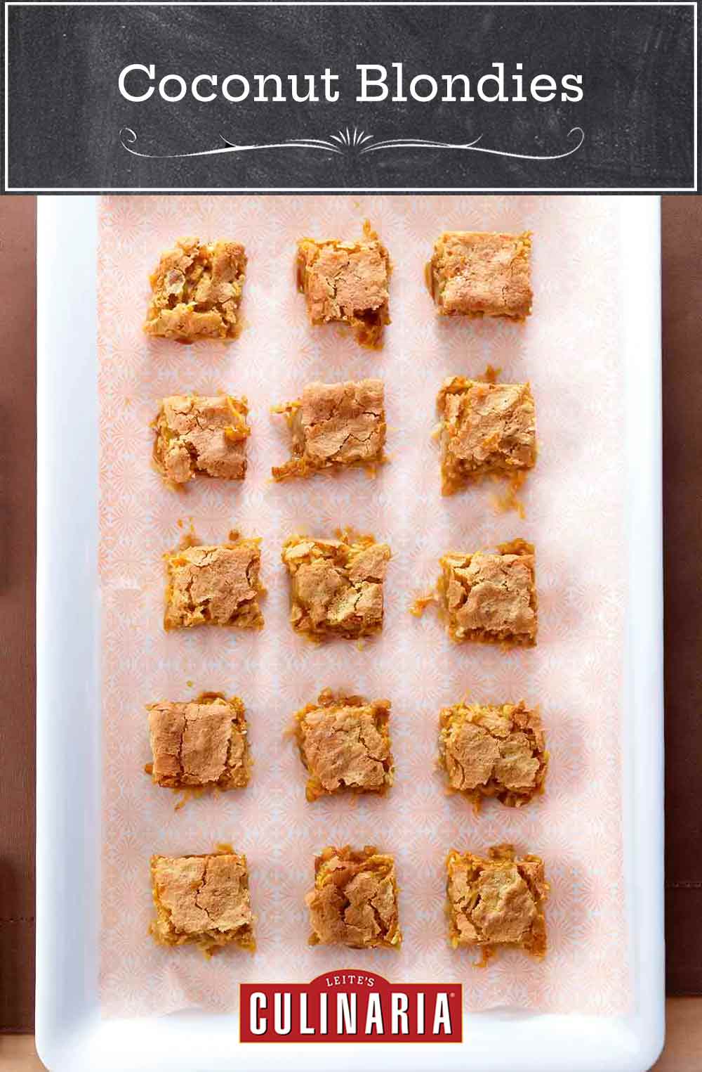 A white baking dish with a piece of patterned parchment and 15 squares of coconut blondies.