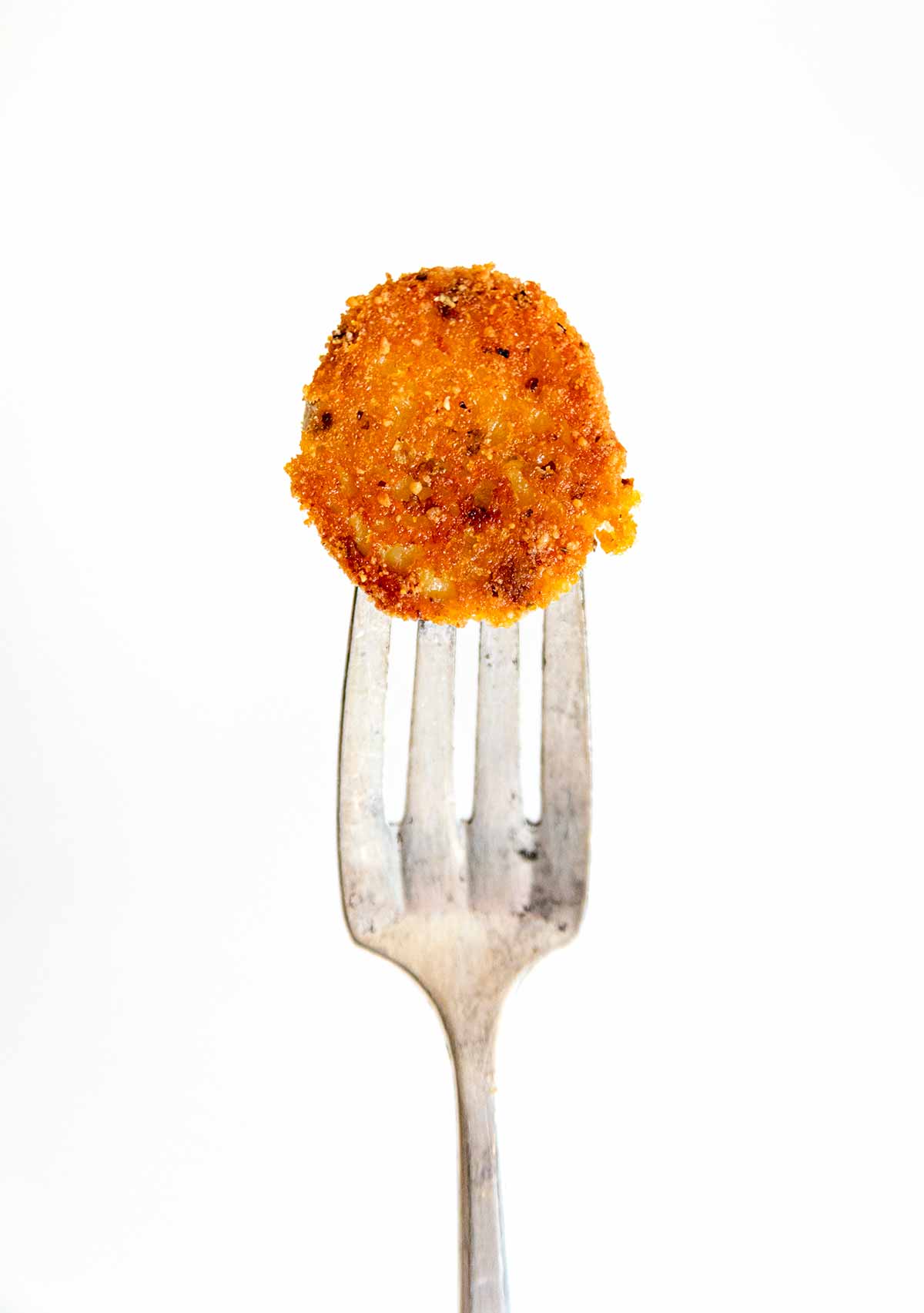 A crispy herbed Parmesan potato on a fork.
