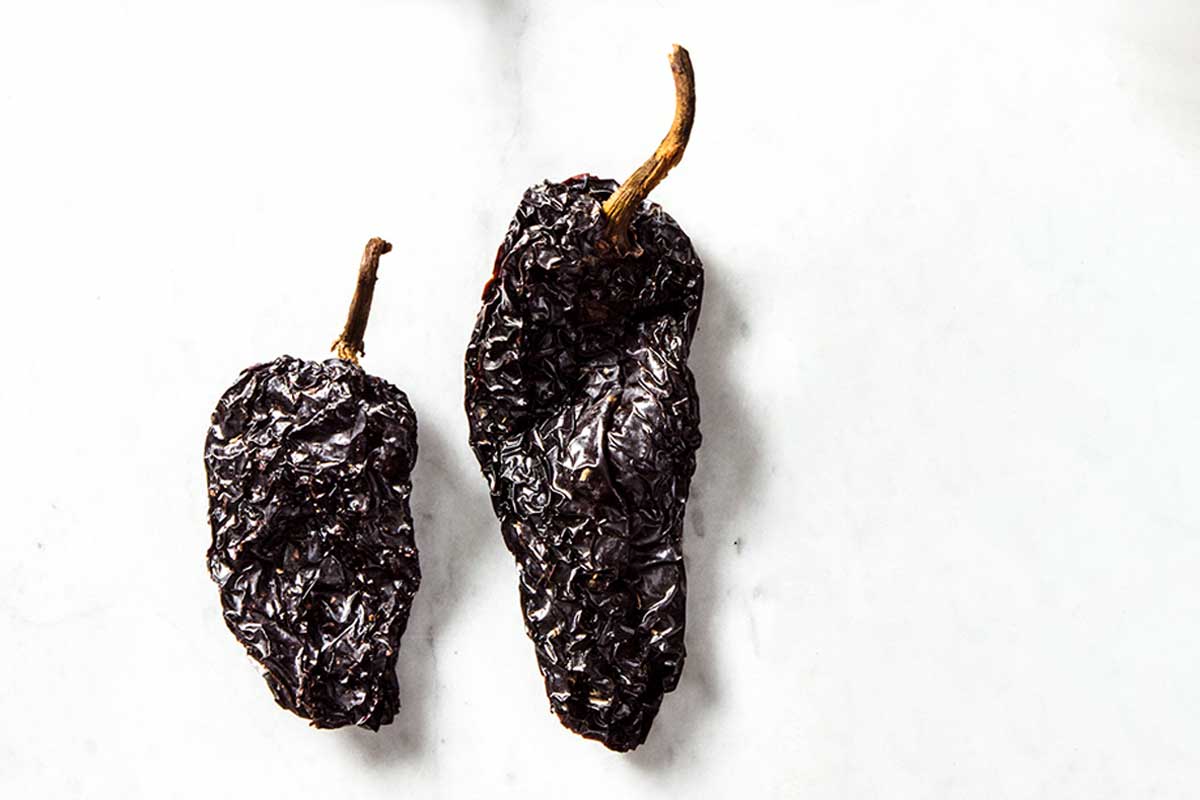 Two dried ancho chile peppers to illustrate the difference among dried chile peppers.