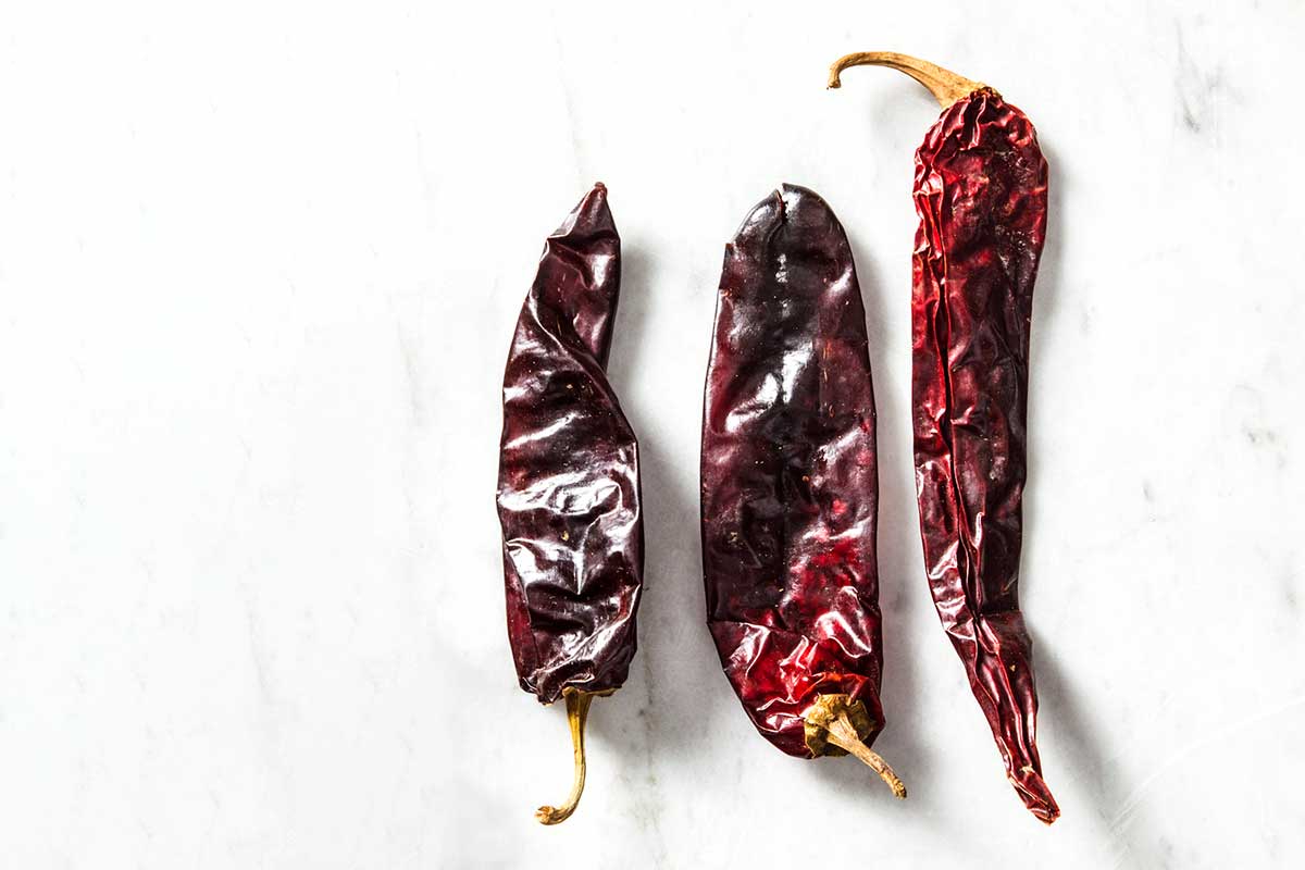 Three dried guajillos chile peppers to illustrate the difference among dried chile peppers.