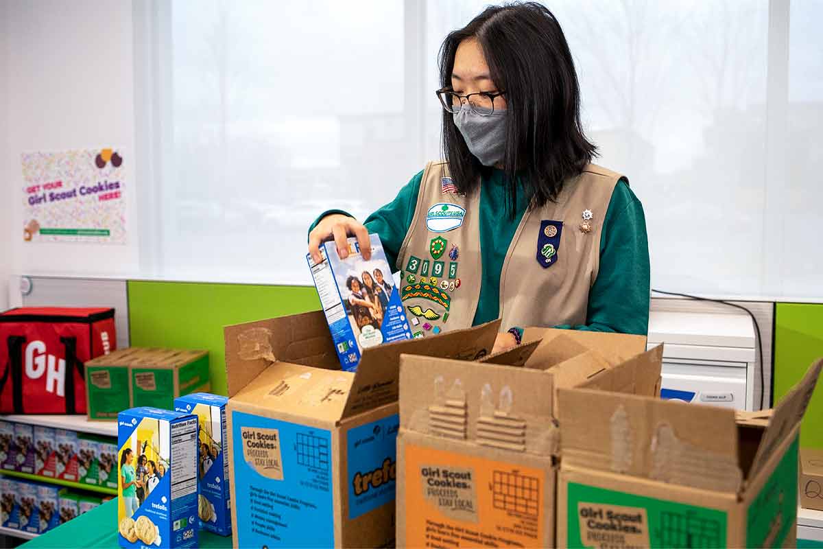A girl scout packaging up boxes of cookies to be delivered by GrubHub.