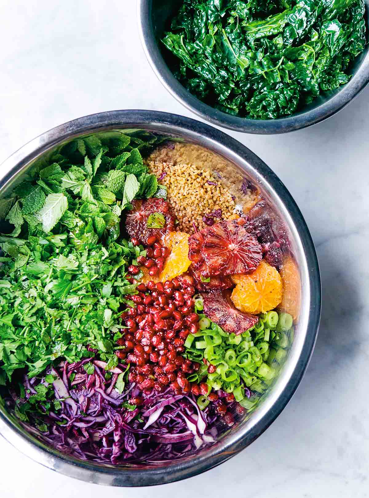 Two bowls filled with the components to make a grain bowl with kale and spiced orange dressing.