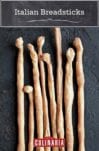 Eight Italian breadsticks, or grissini, lined up next to each other.