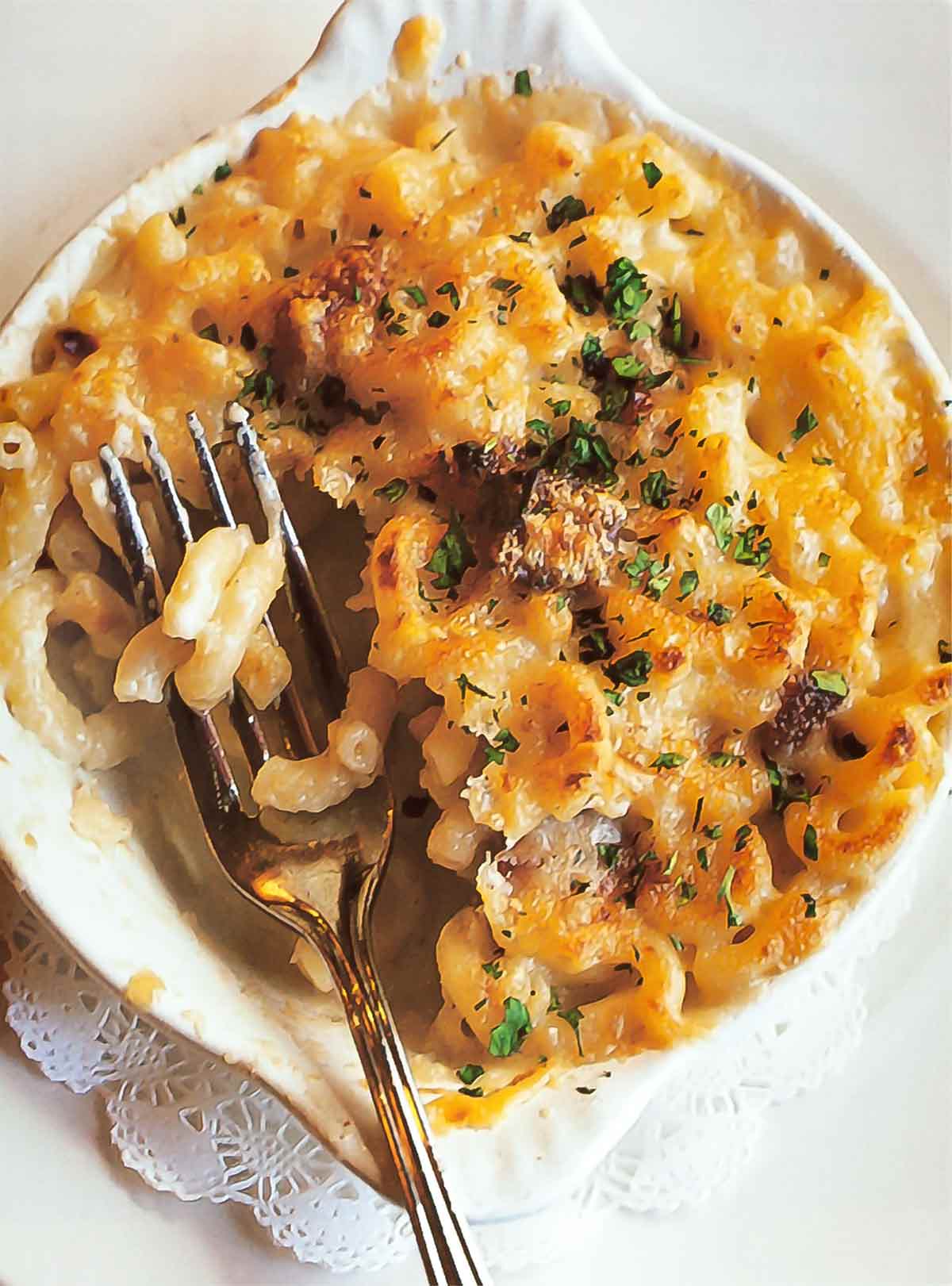 A white dish of macaroni gratin with a fork resting inside.