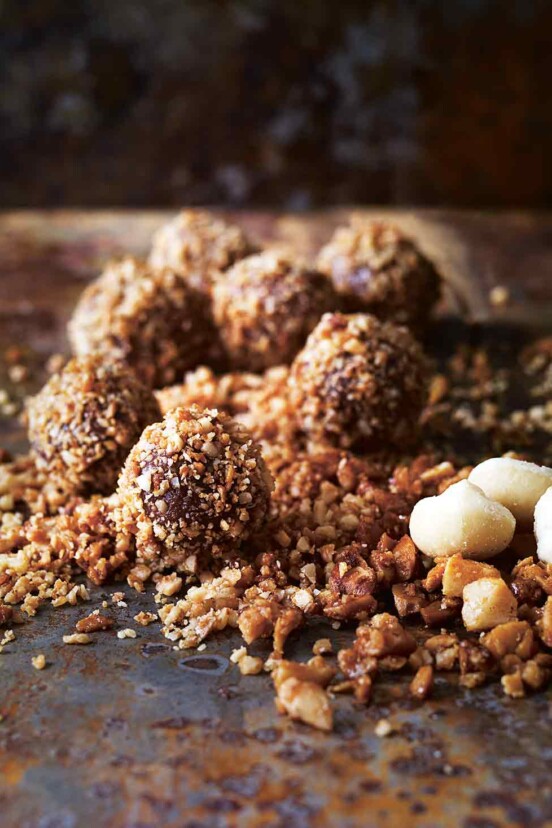 Seven milk chocolate truffles in a pile of candied macadamia nuts.