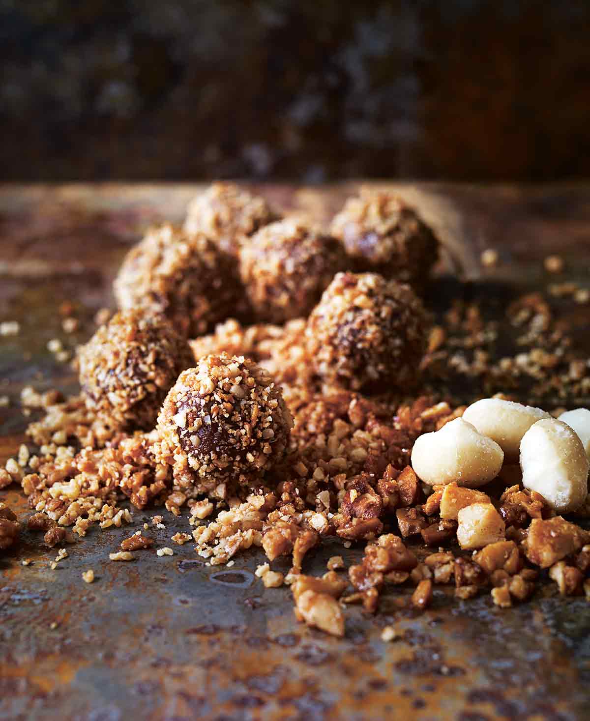 Seven milk chocolate truffles in a pile of candied macadamia nuts.