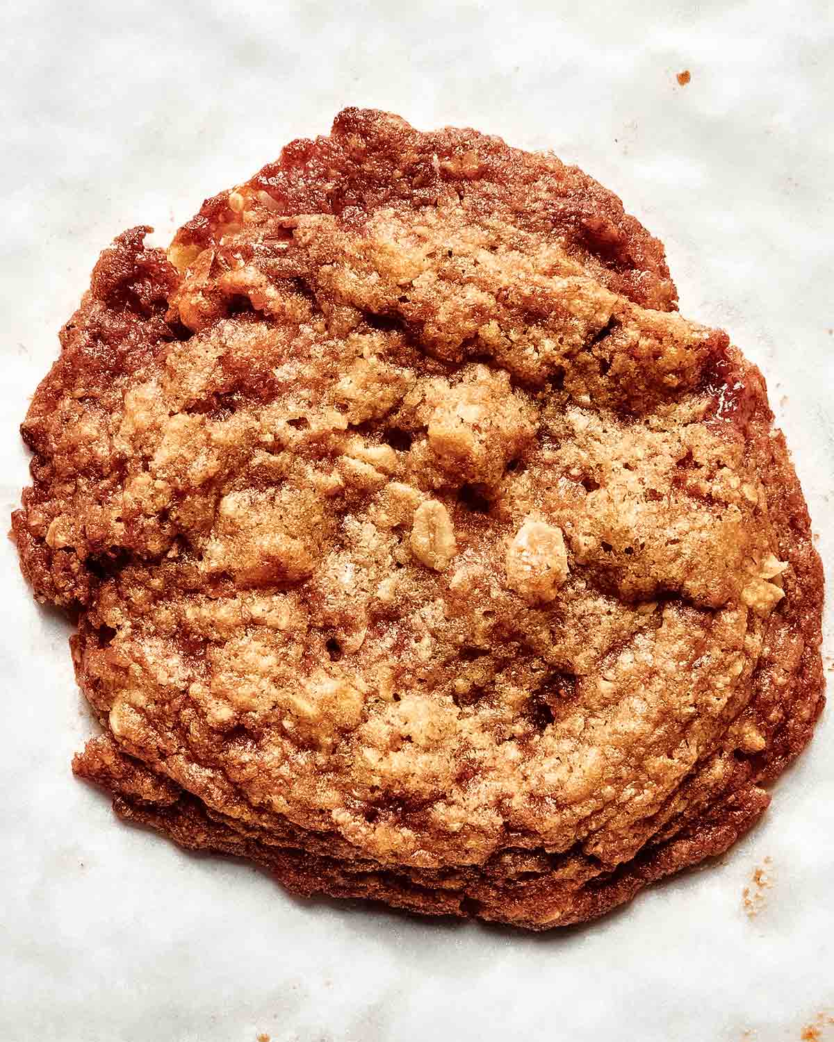 A single oat and pecan brittle cookie on a white background.