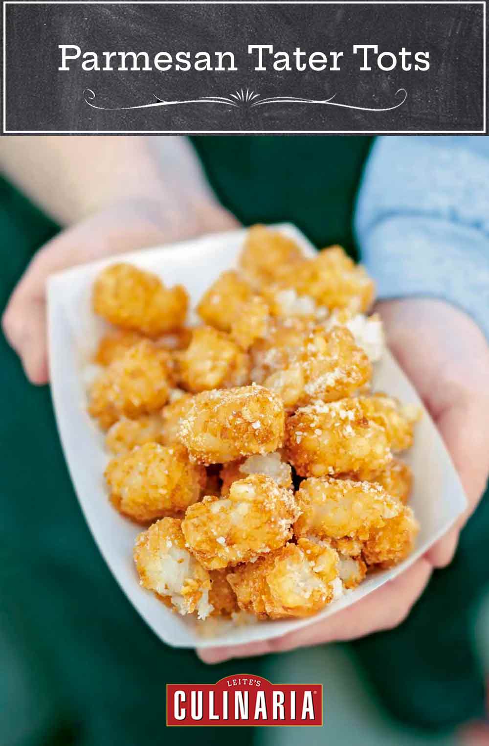 Two hands holding a paper container of tater tots sprinkled with Parmesan cheese