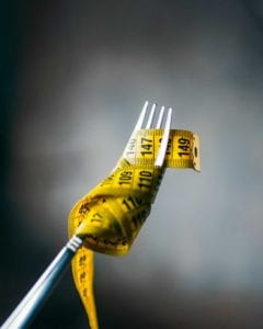 A fork with a measuring tape wrapped around it to illustrate the difference among the most popular diets.