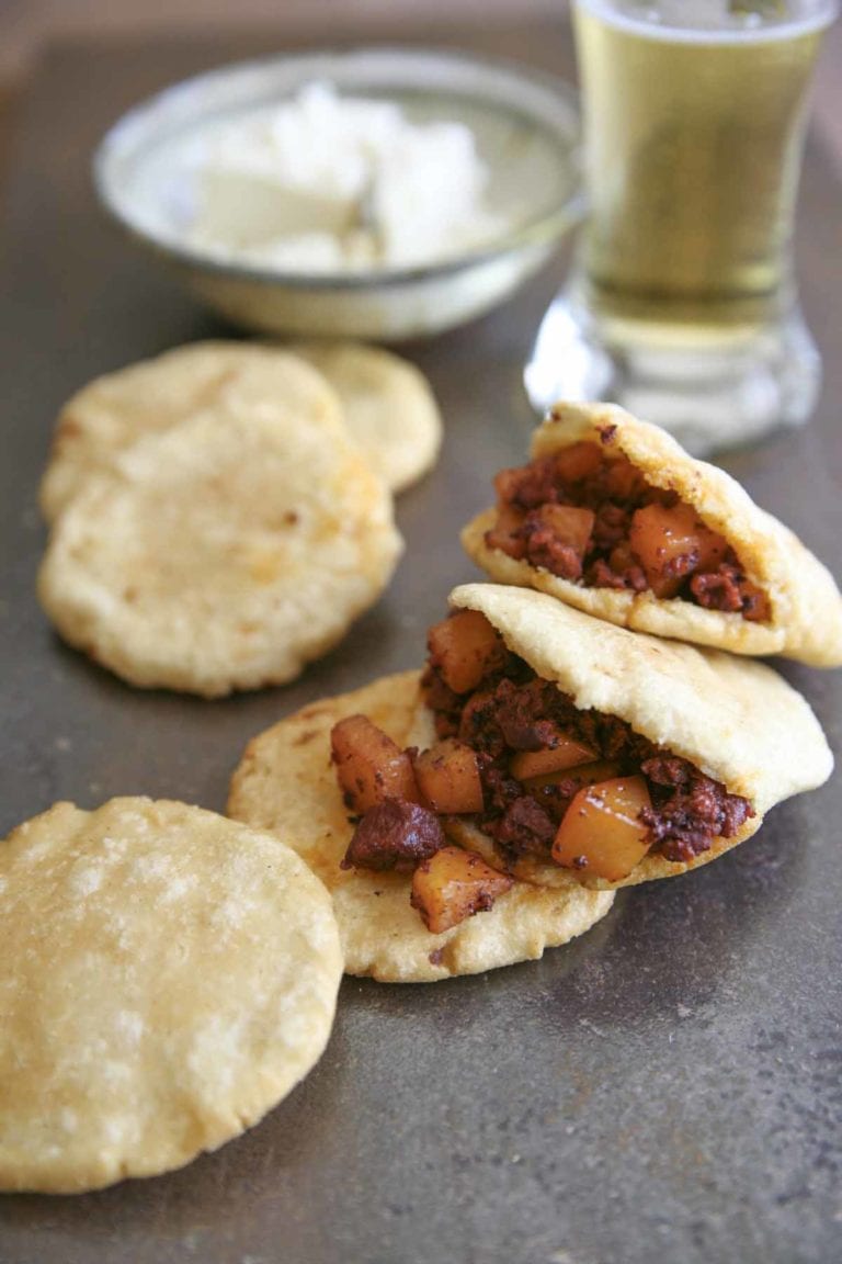 Potatoes with Mexican chorizo tucked inside tortillas with a glass of beer on the side.