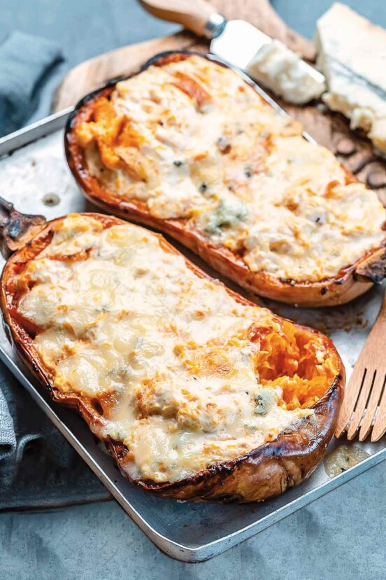 A stuffed roast winter squash with blue cheese on a rimmed baking sheet.