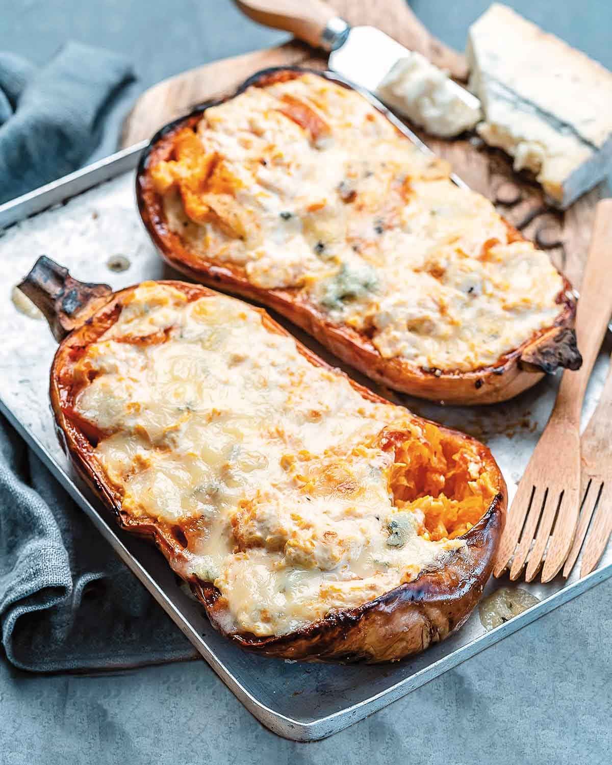 A stuffed roast winter squash with blue cheese on a rimmed baking sheet.