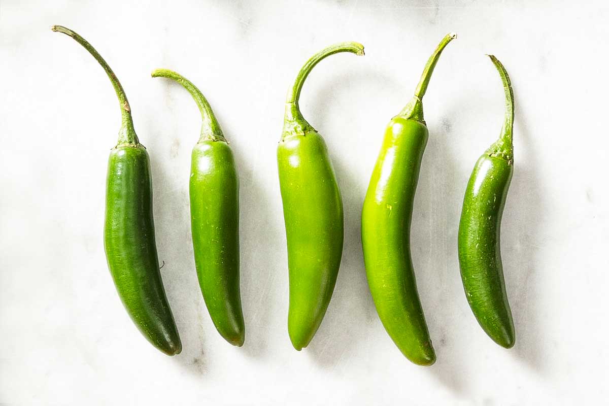Five serrano peppers as illustration for 'what's the difference among chile peppers?'