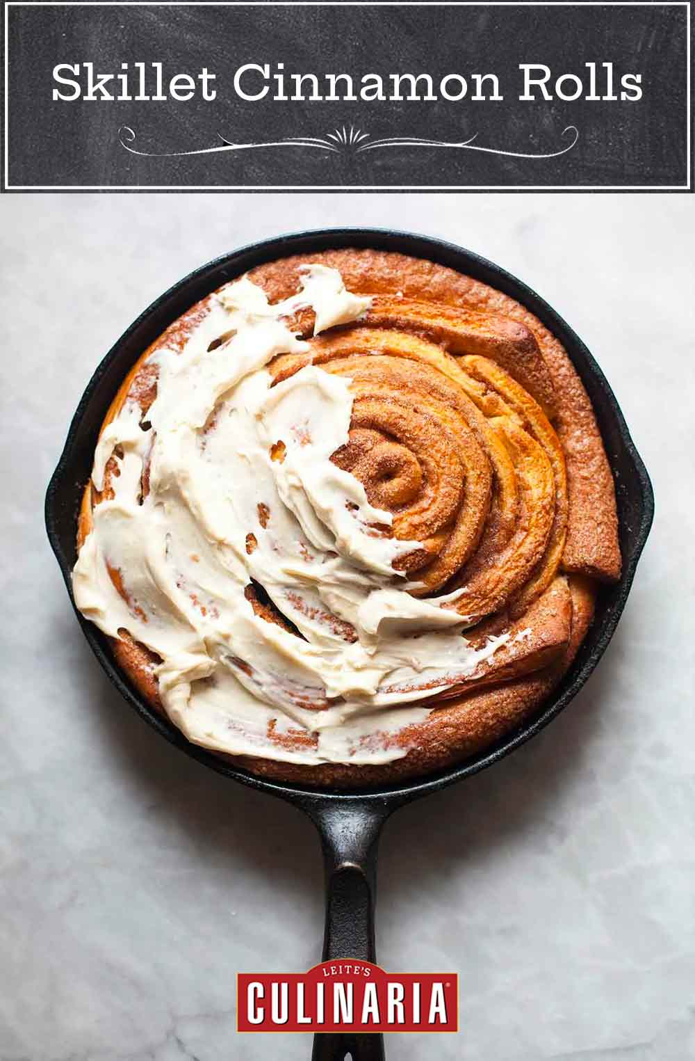 A giant skillet cinnamon roll in a black cast iron pan half cover with cream cheese icing.