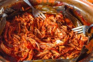A fork in a pot of shredded Yucatan-style slow-roasted pork.