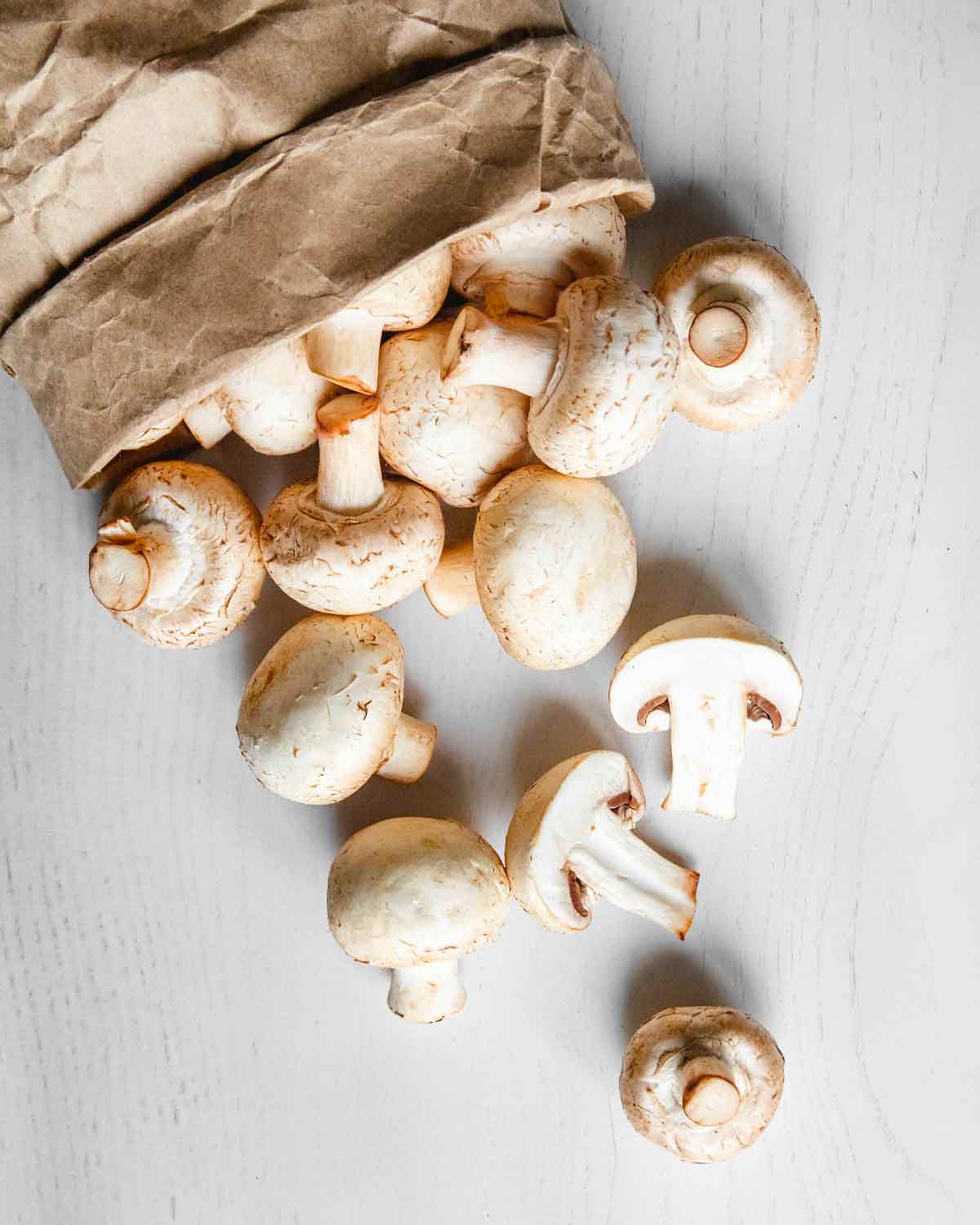 Mushrooms spilling out of a paper bag, one way to store mushrooms so they don't get slimy.