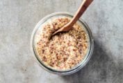 A jar of whole grain mustard with a wooden spoon in it.