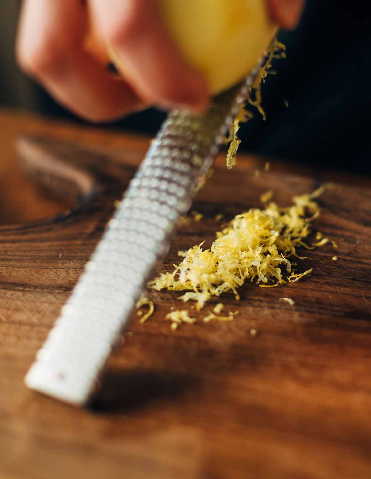 A person zesting a lemon on a microplane to demonstrate how, if you’re like most cooks, you’re using your zester wrong.