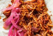 Yucata-style slow-roasted pork piled on a flour tortilla with pickled onions.