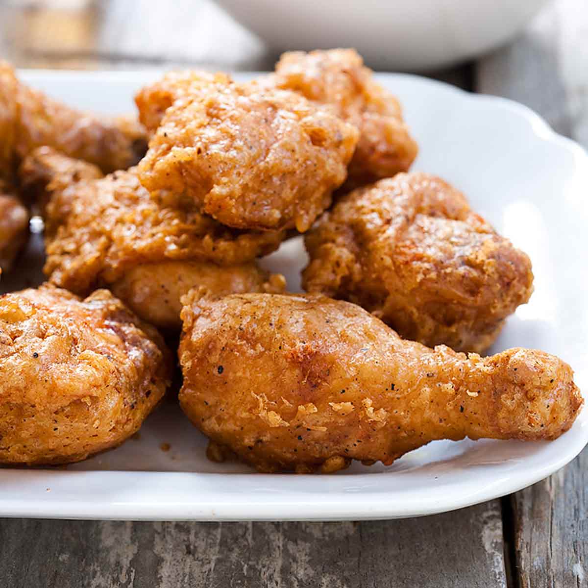 Pieces of batter-fried chicken piled on a white platter.