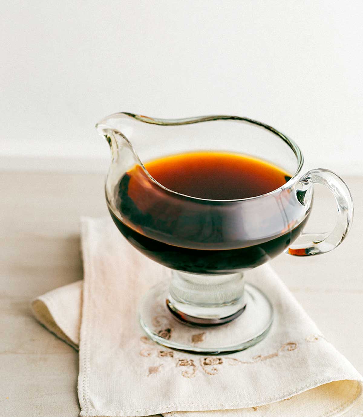 A glass pitcher filled with bourbon syrup on a linen napkin.