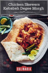 Pieces of chicken skewers in a flat bread with sliced pepper and limes on the side.