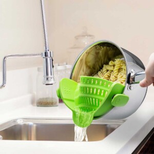 Clip-on Strainer attached to a saucepan filled with pasta at the sink.