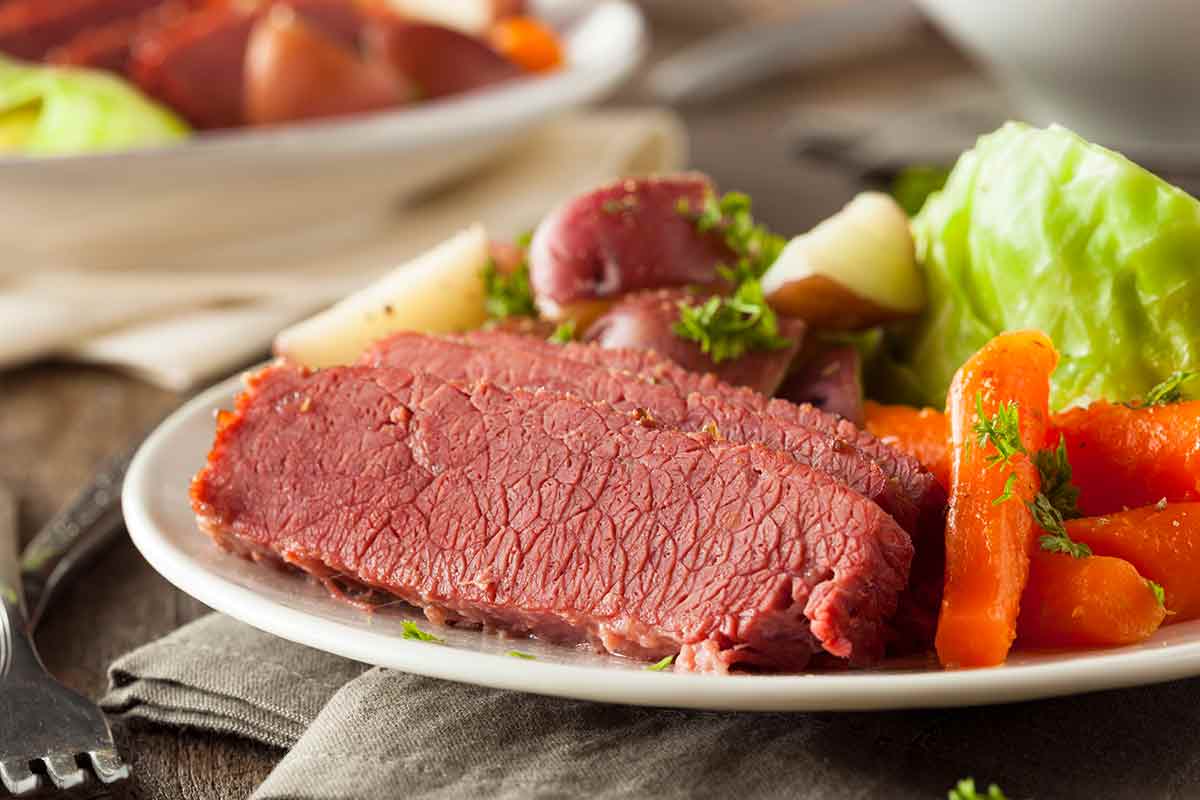A white plate with corned beef and cabbage