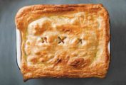 A rectangular dish filled with curry chicken pot pie and topped with puff pastry.