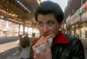 John Travolta eating a double slice of pizza.