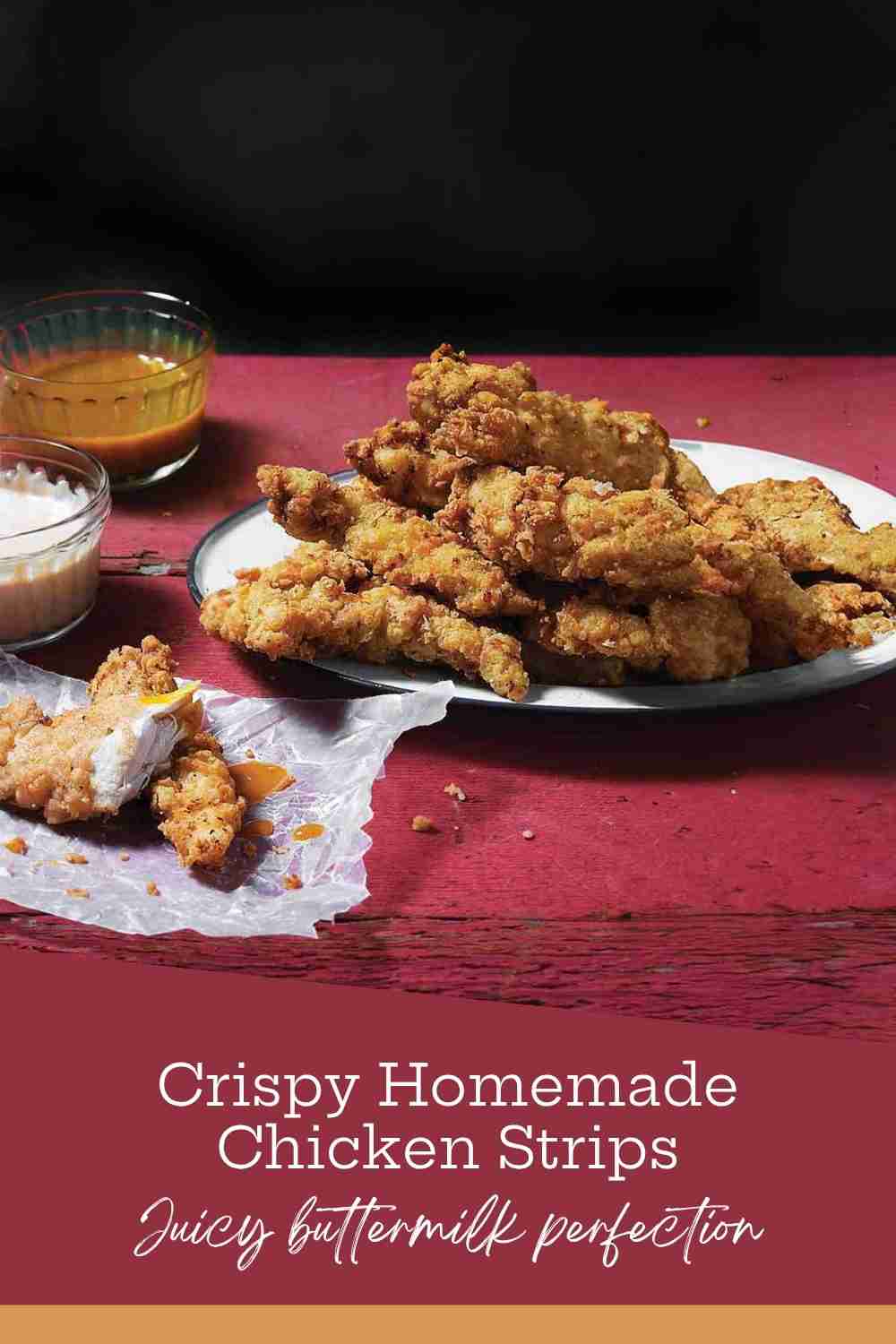 A stack of golden brown crispy chicken strips on a white plate over a rustic red table with dipping sauces.