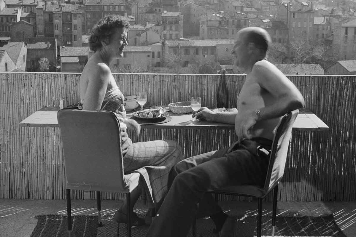 Julia Child and Paul Child at a table overlooking the city with wine and food.