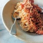 An oval plate topped with lobster fra diavolo and a spoon resting on the side.
