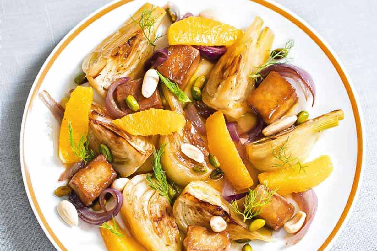 A plate of orange-braised tofu with fennel and onion wedges and orange segments on top.