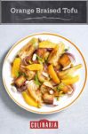 A plate of orange-braised tofu with fennel and onion wedges and orange segments on top.