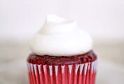A red velvet cupcake with cream cheese frosting on top.