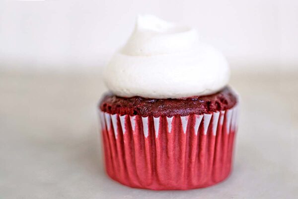 A red velvet cupcake with cream cheese frosting on top.