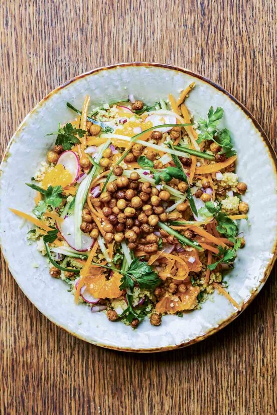 Roasted chickpea salad on a gold-rimmed plate, with orange segments, couscous, cilantro, and shaved carrot.