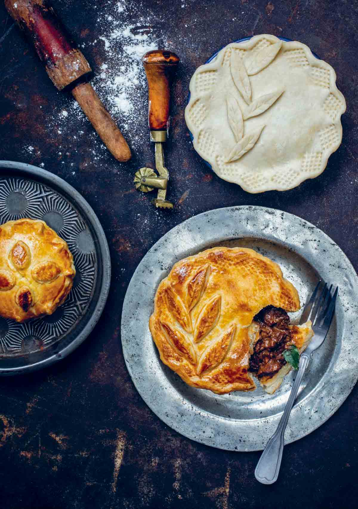 Two steak and ale pies on silver platters.