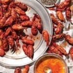 Crawfish piled on a platter and on newspaper beneath it with a bowl of butter beside for a tandoori masala. crawfish boil.