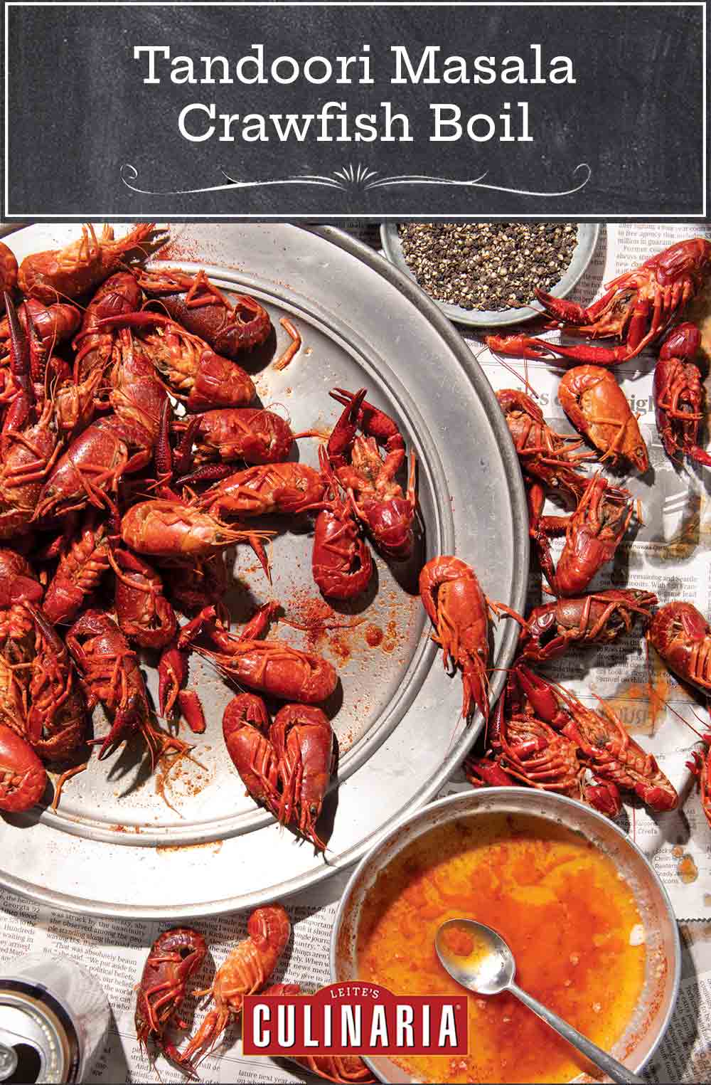 Crawfish piled on a platter and on newspaper beneath it with a bowl of butter beside for a tandoori masala crawfish boil.