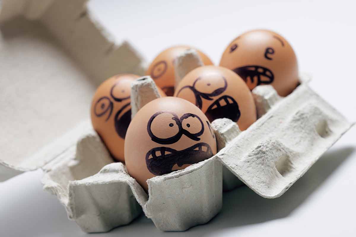 a six-pack of eggs with scared faces drawn on them