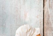 An ice cream cone with a scoop of toasted coconut ice cream on a white wood background.